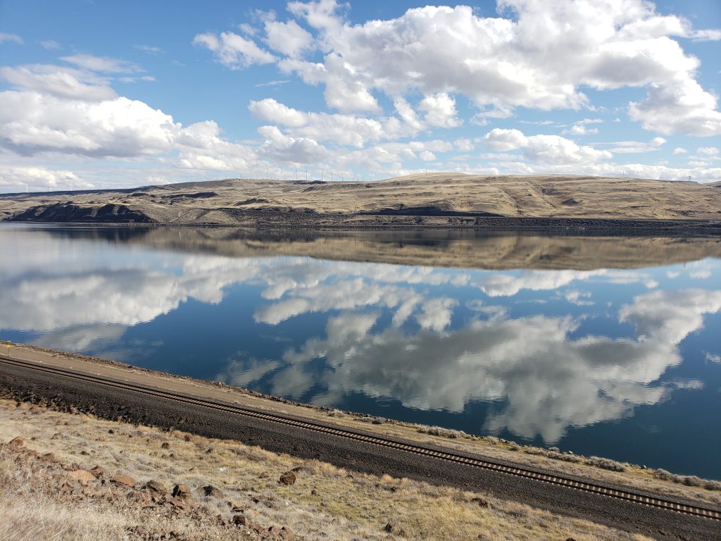 The magnificent Columbia River is truly showing out, still enough to reflect puffy blue clouds drifting overhead.